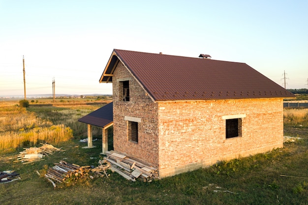 Casa de ladrillo sin terminar con techo cubierto con láminas de metal en construcción.