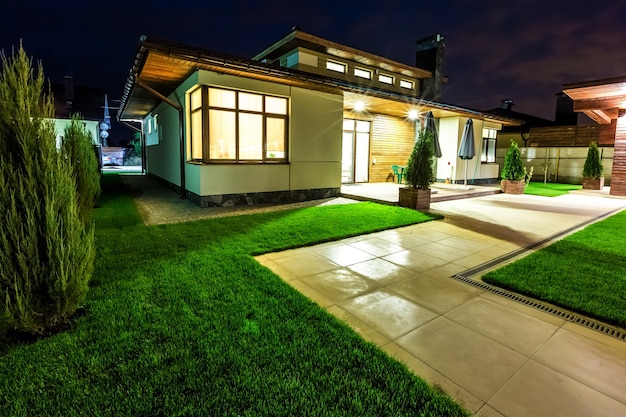 Casa de lujo independiente en la noche - vista desde el exterior del patio trasero. Arquitectura de diseño moderno, hermosa casa, escena nocturna.