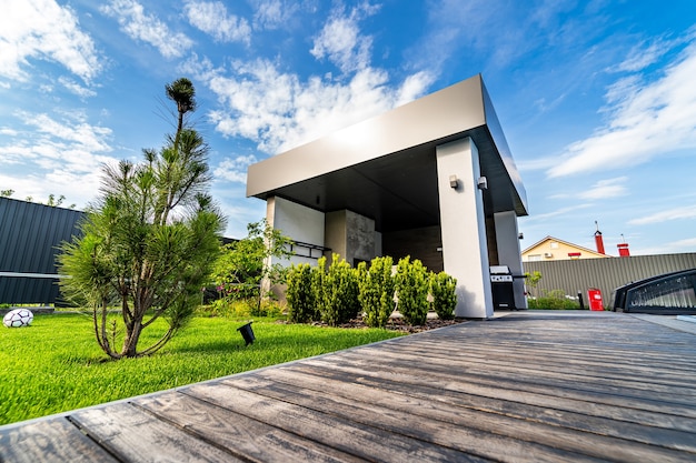 Casa luxuosa com garagem. Céu azul acima. Ninguém no quintal. Arquitetura moderna. Casa aconchegante e moderna. Arquitetura moderna.