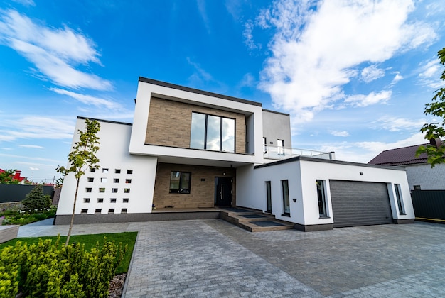 Casa luxuosa moderna com garagem. Céu azul acima. Ninguém no quintal. Arquitetura moderna.