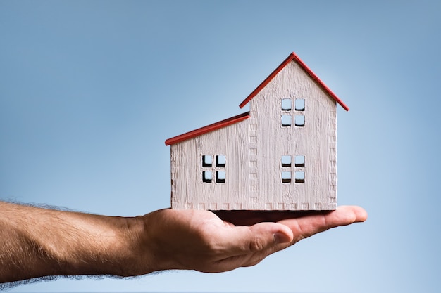 Casa de madera blanca en una mano masculina. Concepto de vivienda