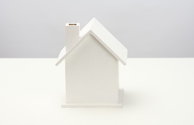 Foto casa de madera blanca sobre un fondo gris. concepto de alquiler, compra y venta de bienes raíces. servicios inmobiliarios, reparación y mantenimiento de edificios