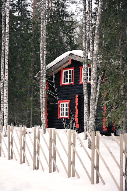 Casa de madera en bosque de invierno con madera.