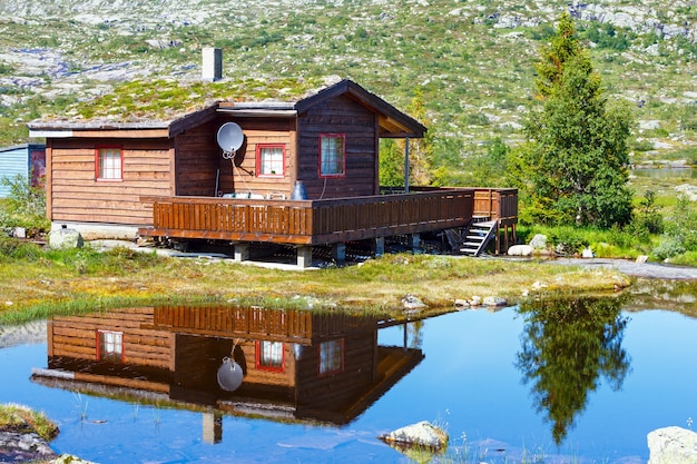 Casa de madera cerca del pequeño lago de montaña de verano.