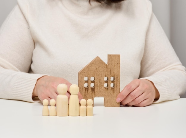 Casa de madera y figuras de una familia Concepto de seguro inmobiliario familia feliz