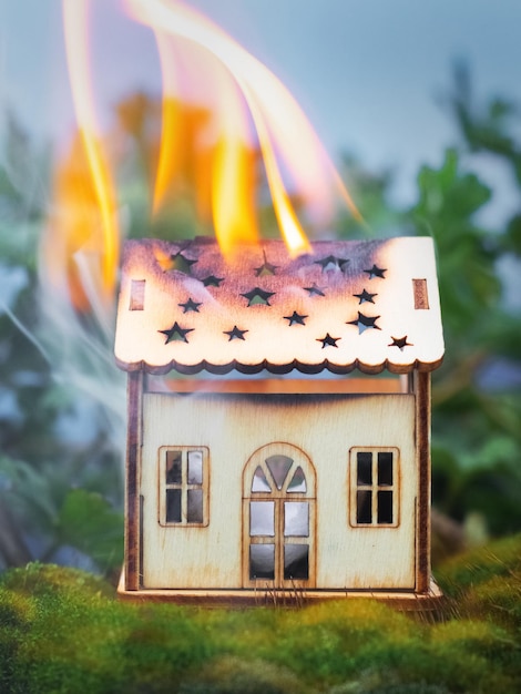 Una casa de madera de juguete está ardiendo en la naturaleza Concepto de fuego Seguridad contra incendios