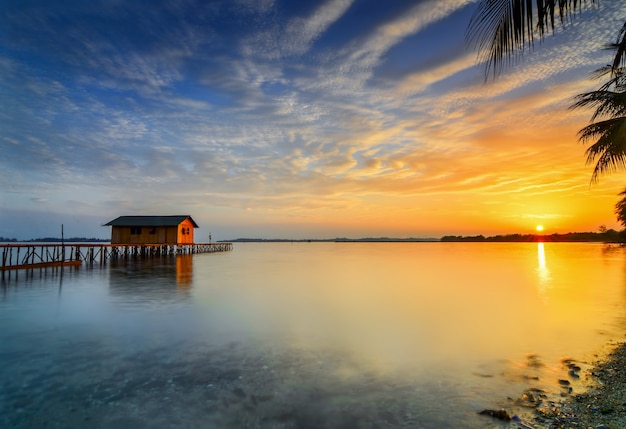 casa de madera en el mar en una hermosa puesta de sol