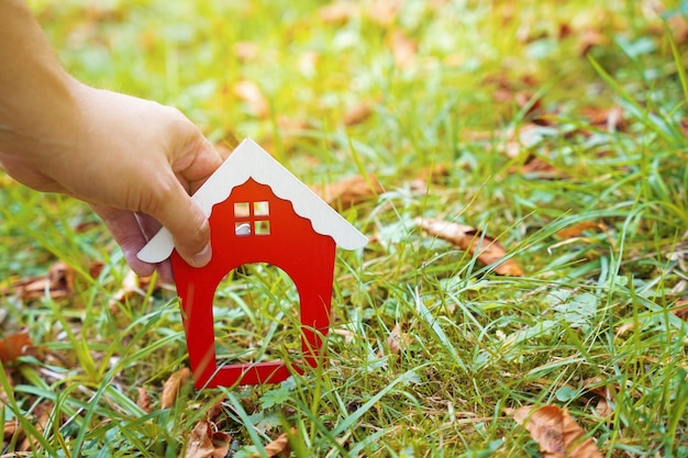 Casa de madera en miniatura en manos de un hombre al aire libre Concepto inmobiliario Hogar ecológico Comprar una vivienda fuera de la ciudad Techo rojo Enfoque selectivo