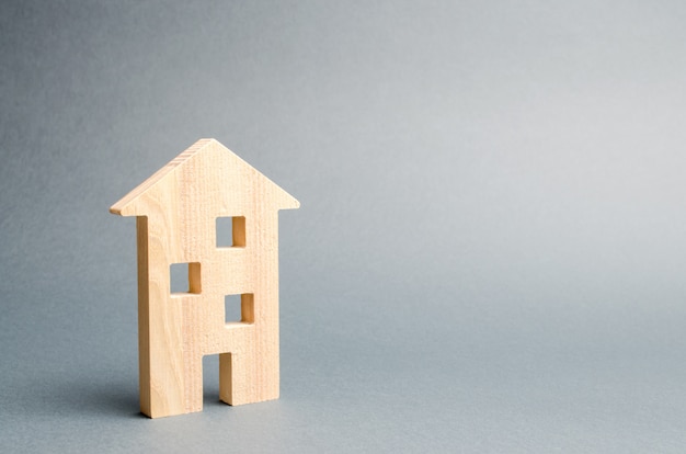 Casa de madera en miniatura sobre un fondo gris.