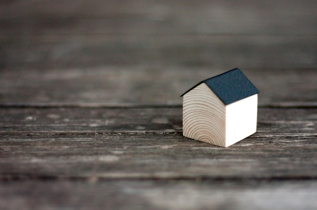 Casa de madera en miniatura con techo de metal negro sobre fondo de madera rústica