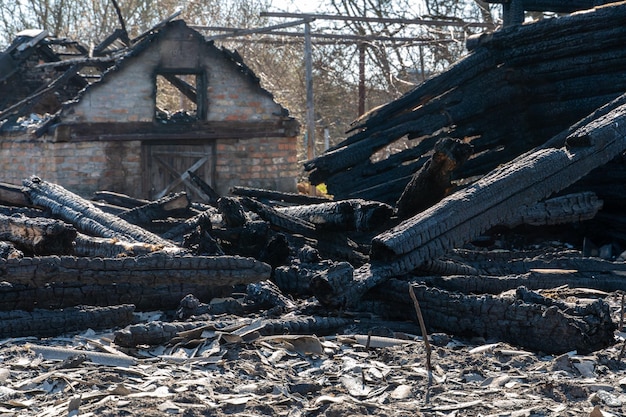 Una casa de madera en el pueblo se incendió debido a un incendio forestal Tablas carbonizadas y varias cosas yacen en el suelo cubiertas de ceniza y humo