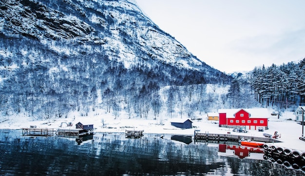 Casa de madera roja a orillas del fiordo noruego hermoso paisaje montañoso en invierno