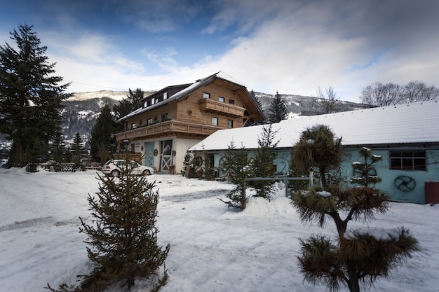 Casa de madera tradicional austriaca en bosque de pinos en día de nieve