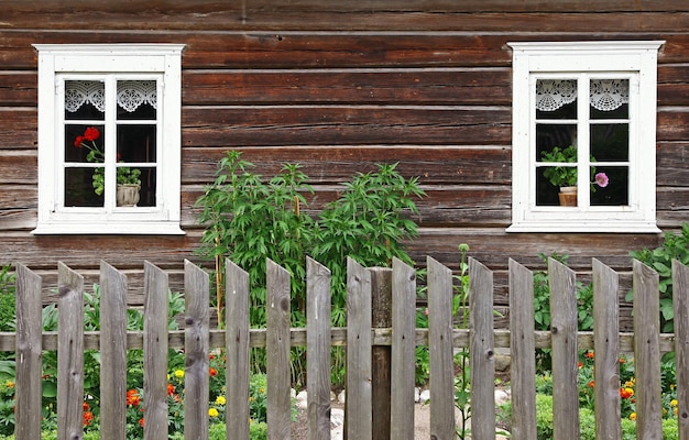 Una casa de madera con una valla y una ventana con una cortina de encaje.