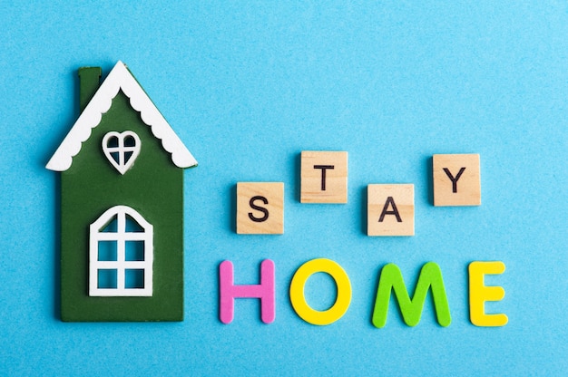 Casa de madera verde y cartel Stay Home