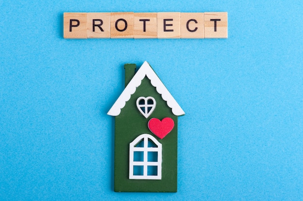 Casa de madera verde y signo de protección en azul