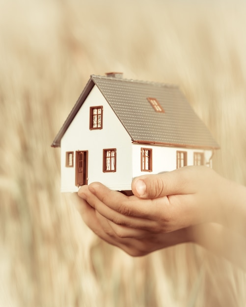 Casa en manos de los niños contra el fondo amarillo otoño Concepto inmobiliario