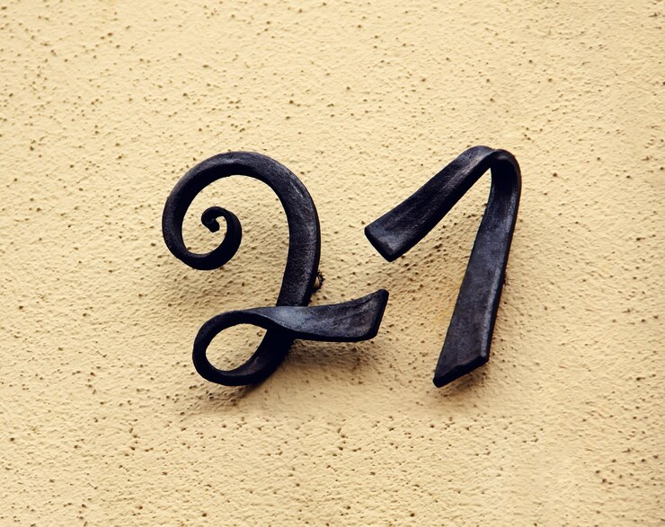 Foto casa de metal número veintiuno. letras negras separadas en una pared.