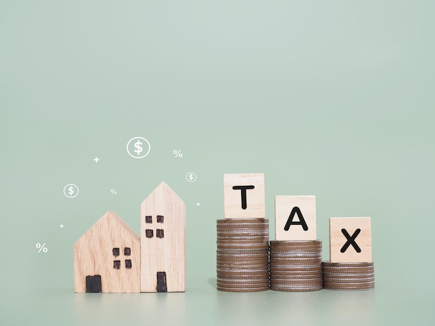 Casa en miniatura Bloques de madera con la palabra TAX y pila de monedas El concepto de pago de impuestos para la casa Inversión inmobiliaria Hipoteca de la casa Inmobiliaria