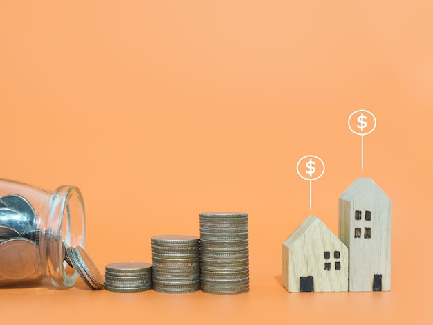 Casa en miniatura con iconos de monedas de dólar y pila de monedas El concepto de precio de la casa Inversión inmobiliaria Hipoteca de casa Inmobiliaria