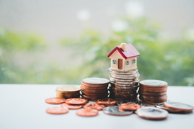 Casa miniatura en monedas de pila usando como propiedad y concepto financiero