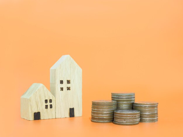 Casa en miniatura y pila de monedas El concepto de ahorrar dinero para la casa Inversión inmobiliaria Hipoteca de casa Inmobiliaria