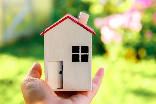 Foto casa modelo em miniatura na mão da mulher feminina no fundo verde ao ar livre eco vila abstrato ambi ...