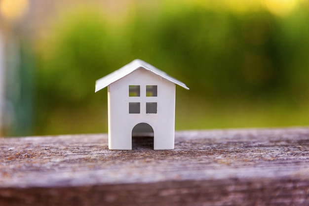 Casa modelo de juguete blanco en miniatura en fondo de madera cerca de fondo verde ecológico