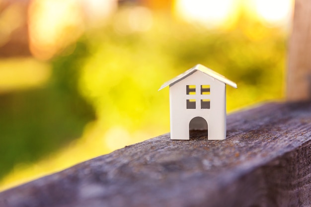 Casa modelo de juguete blanco en miniatura en fondo de madera cerca de fondo verde.