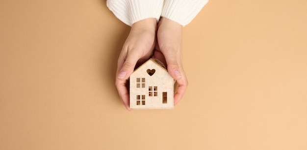 Foto casa modelo en miniatura de madera sobre fondo marrón concepto de seguro inmobiliario protección del medio ambiente
