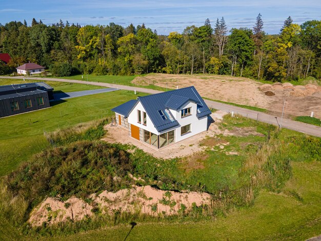 Casa moderna de construção recente com telhado de metal e grandes janelas num cenário rural