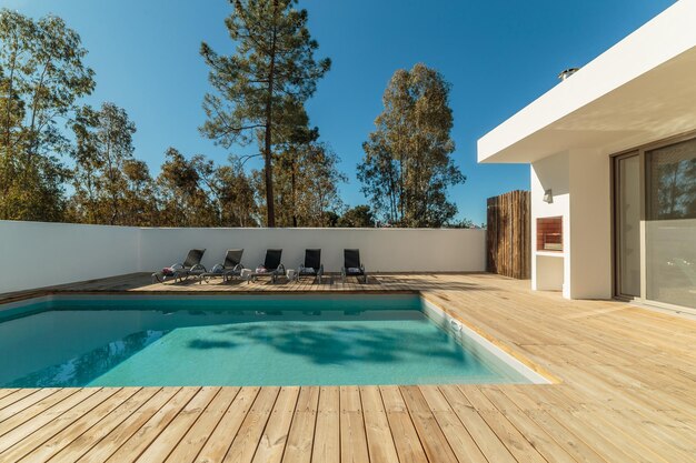 Casa moderna con jardín, piscina y deck de madera.