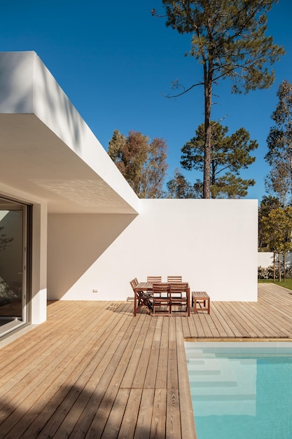 Foto casa moderna con jardín, piscina y deck de madera.