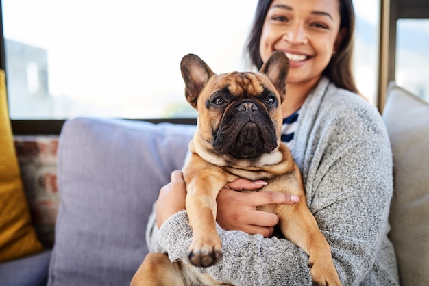 Una casa no es un hogar sin un lindo compañero Retrato de una mujer joven relajándose con su perro en casa