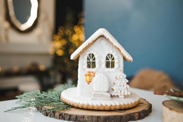 Casa de pan de jengibre, concepto de vacaciones de Navidad y feliz año nuevo. Casa de pan de jengibre casera con ventanas de caramelo en una mesa de madera con adornos navideños. Ánimo de vacaciones