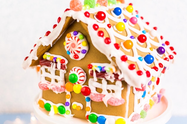 Casa de pan de jengibre decorada con glaseado real blanco y caramelos brillantes.