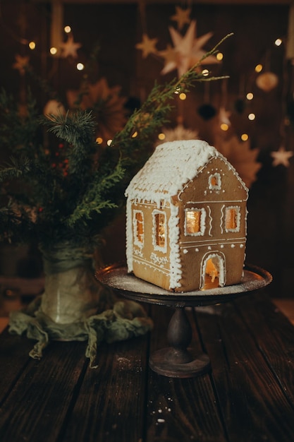 Casa de pan de jengibre hecha a mano sobre un fondo oscuro de Navidad