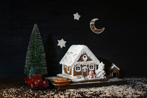 Casa de pan de jengibre junto al coche de juguete y el árbol de Navidad. Feliz navidad y próspero año nuevo.