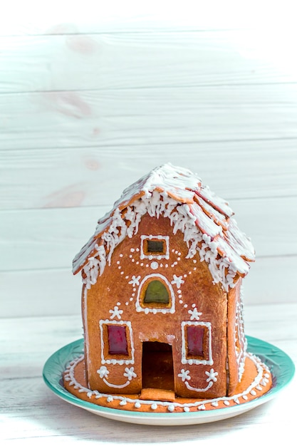 Casa de pan de jengibre de Navidad con esmalte sobre mesa de madera