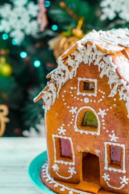 Casa de pan de jengibre de Navidad con esmalte sobre mesa de madera