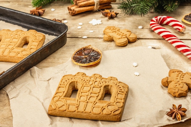 Casa de pan de jengibre de Navidad y hombres de pan de jengibre. Diseño festivo tradicional de Año Nuevo, proceso de cocción. Fondo de madera vieja, estilo rústico, primer plano