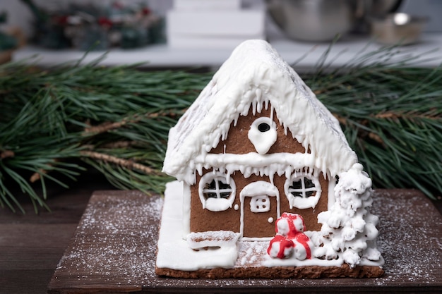 Casa de pan de jengibre sobre soporte de madera. Feliz navidad de fondo. Productos horneados de Navidad.