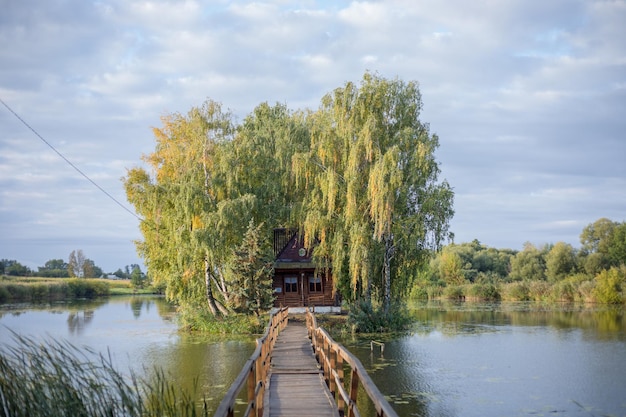 Casa de pescador con un puente peatonal de madera en una pequeña isla en medio del lago Vista otoñal Old Solotvyn village Ucrania