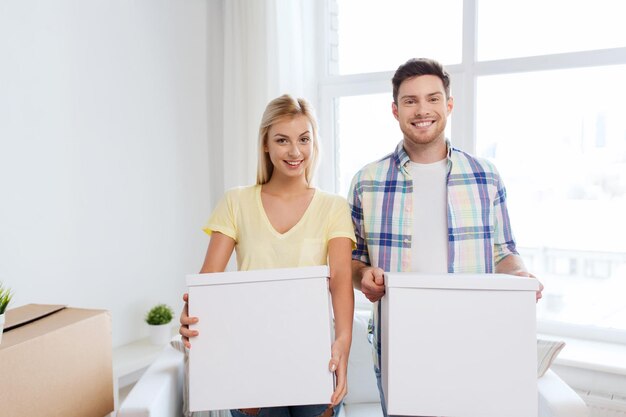 casa, pessoas, reparação e conceito imobiliário - casal sorridente com grandes caixas de papelão movendo-se para um novo lugar