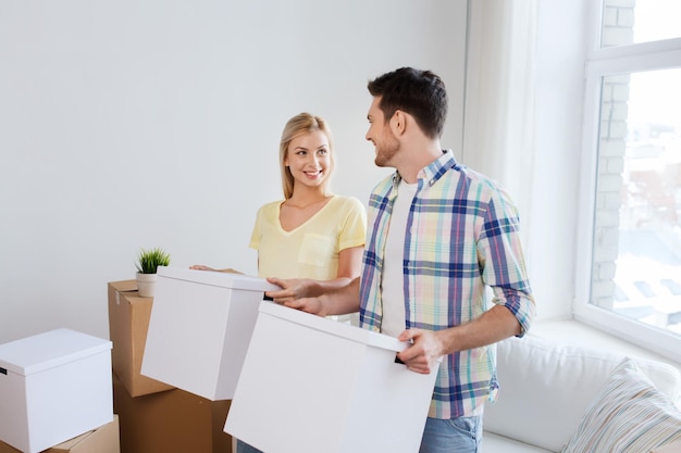 casa, pessoas, reparação e conceito imobiliário - casal sorridente com grandes caixas de papelão movendo-se para um novo lugar