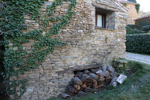 Una casa de piedra con hiedra verde y troncos de madera para leña