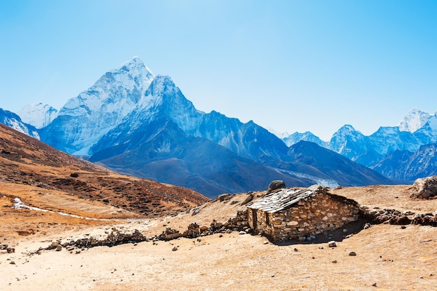 Casa de piedra en las montañas y vista del monte Ama Dablam en el Himalaya, Nepal. Valle de Khumbu, región del Everest