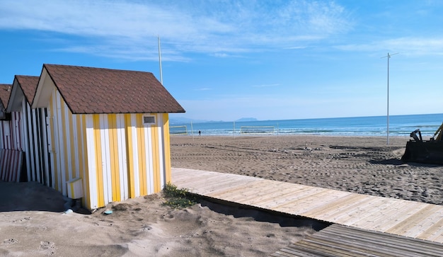 Una casa de playa de rayas amarillas y blancas con un cielo azul de fondo