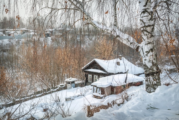 Casa de pueblo de madera a la luz de un día soleado de invierno cubierto de nieve