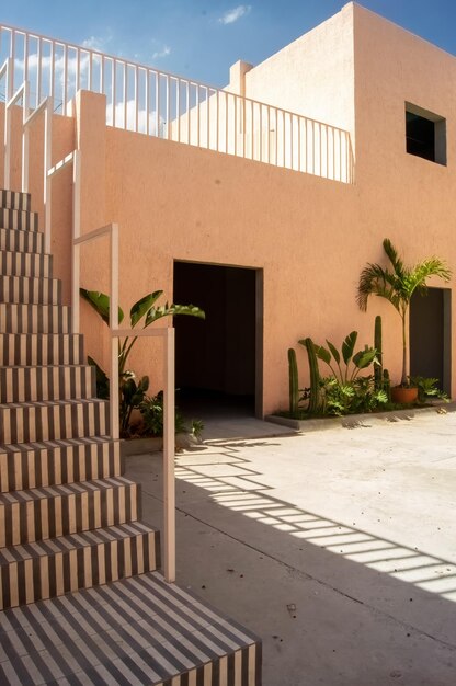 Casa regionalista pintada de rosa con escalera de hierro blanco, un pasamanos es visible en la parte superior